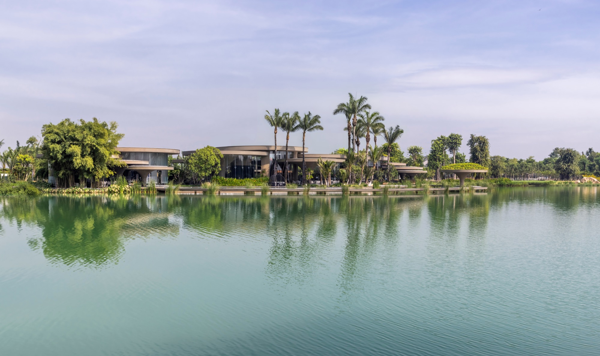 The clubhouse seen from across the lake, low among palms and trees