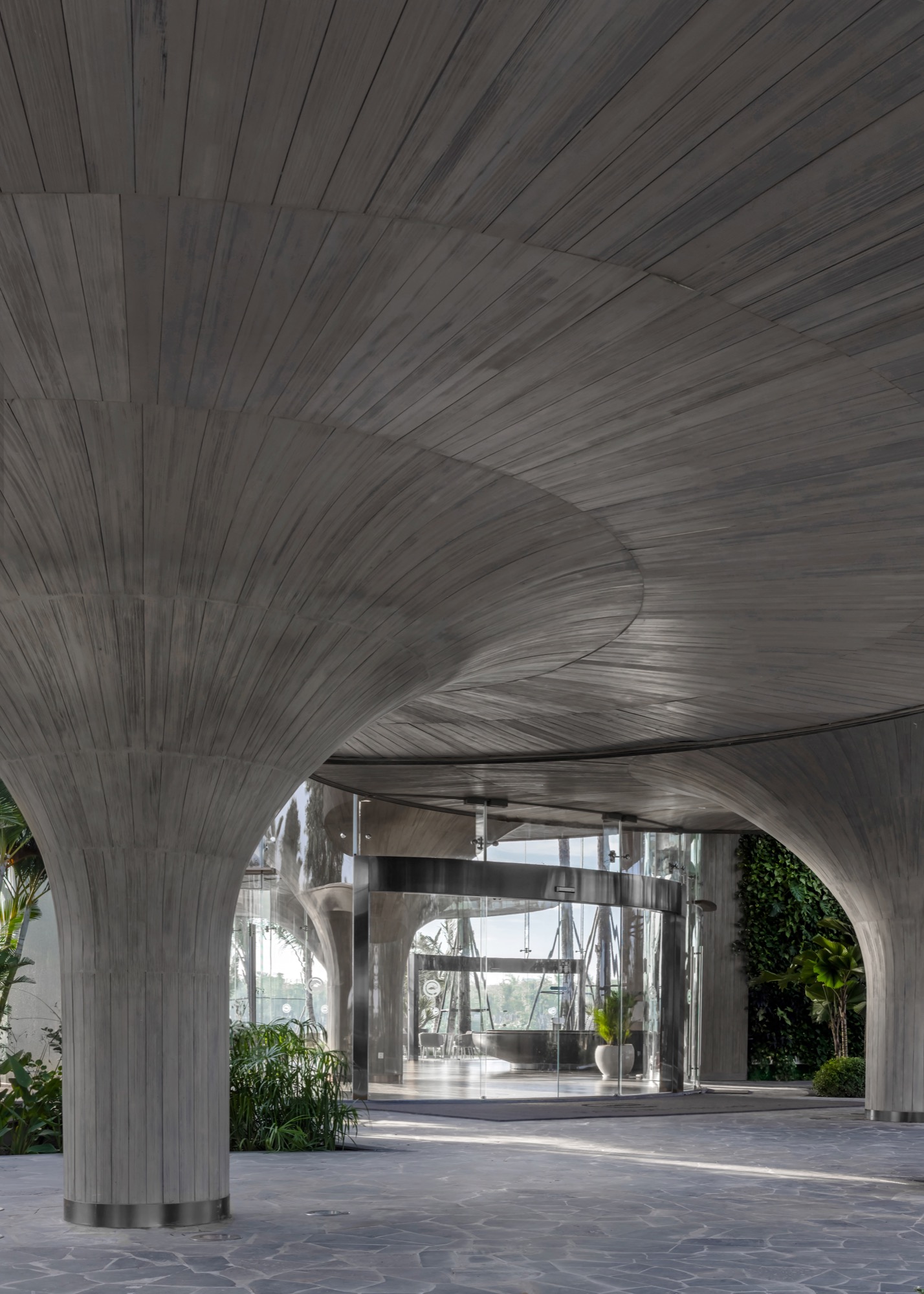 Entrance beneath a flared concrete column and curved roof