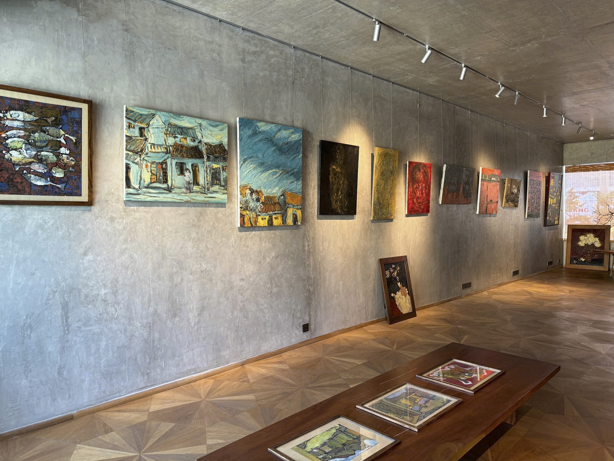 Gallery wall with paintings on bare concrete