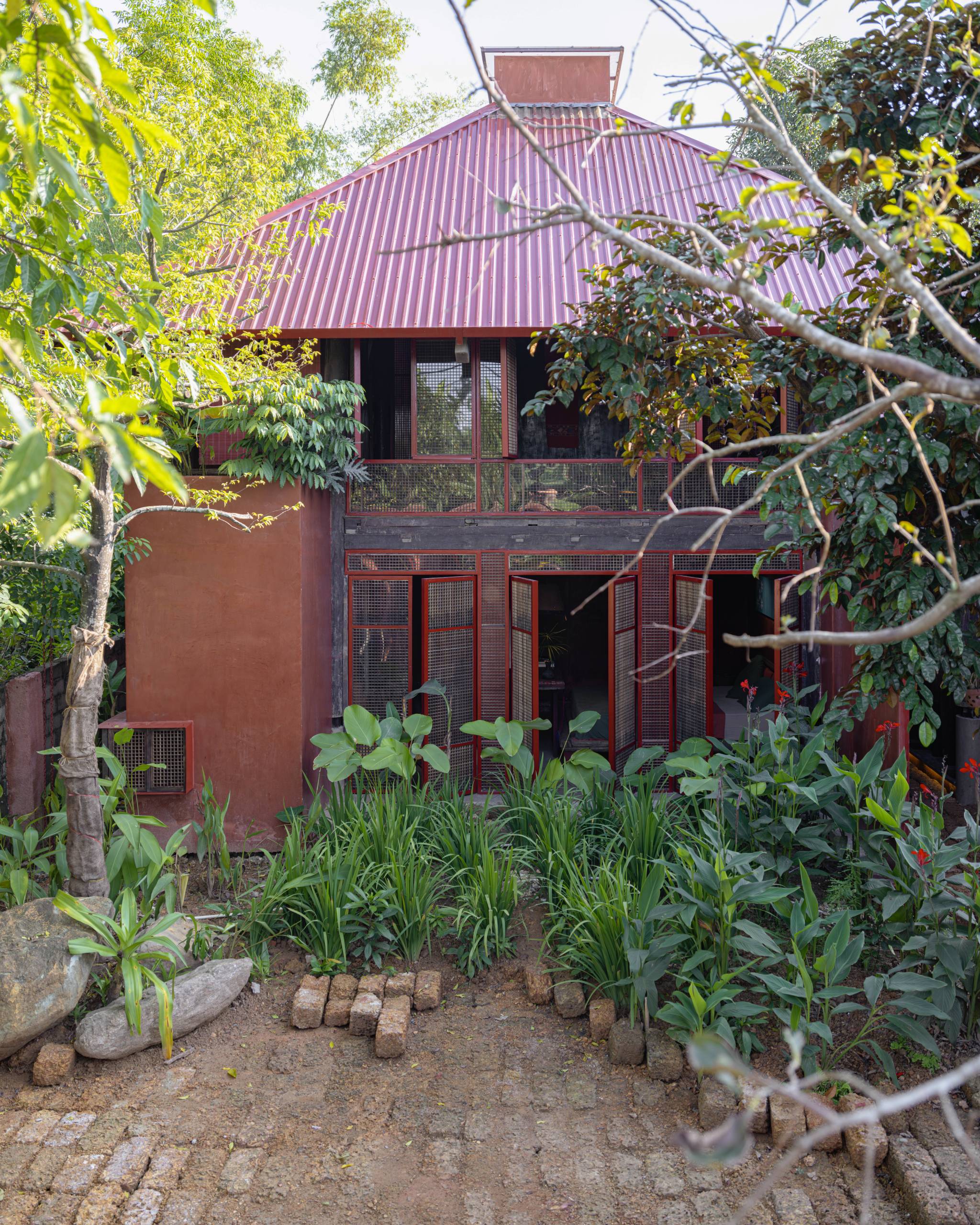 The house behind the garden under a red metal roof